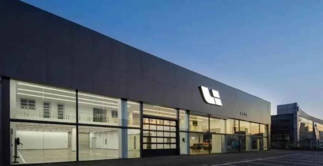 Li Auto dealership at dusk with a long dark facade, glazed showroom and the Li logo