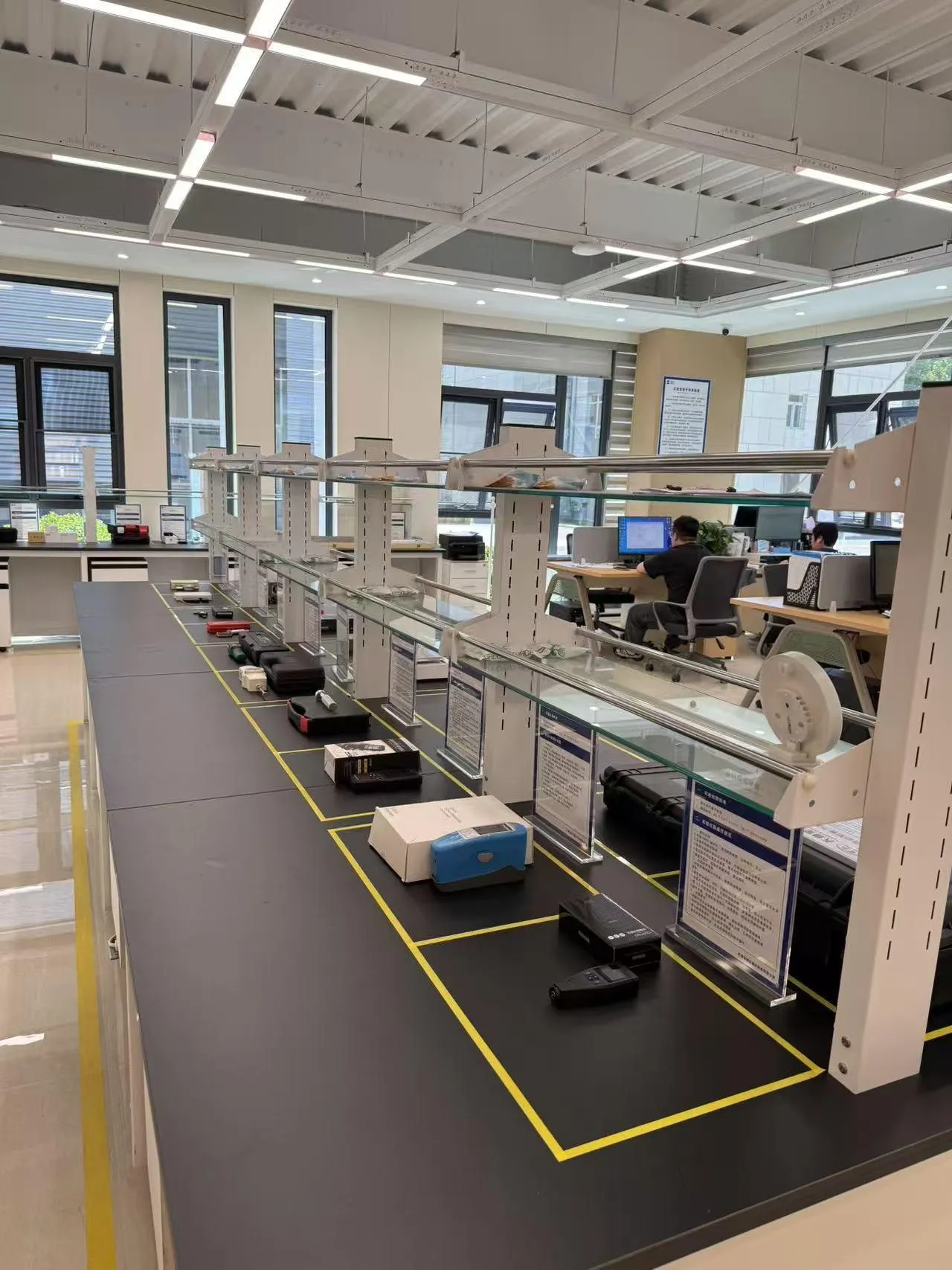 BHS testing laboratory: a long workbench of instruments and test samples, with engineers working in the background